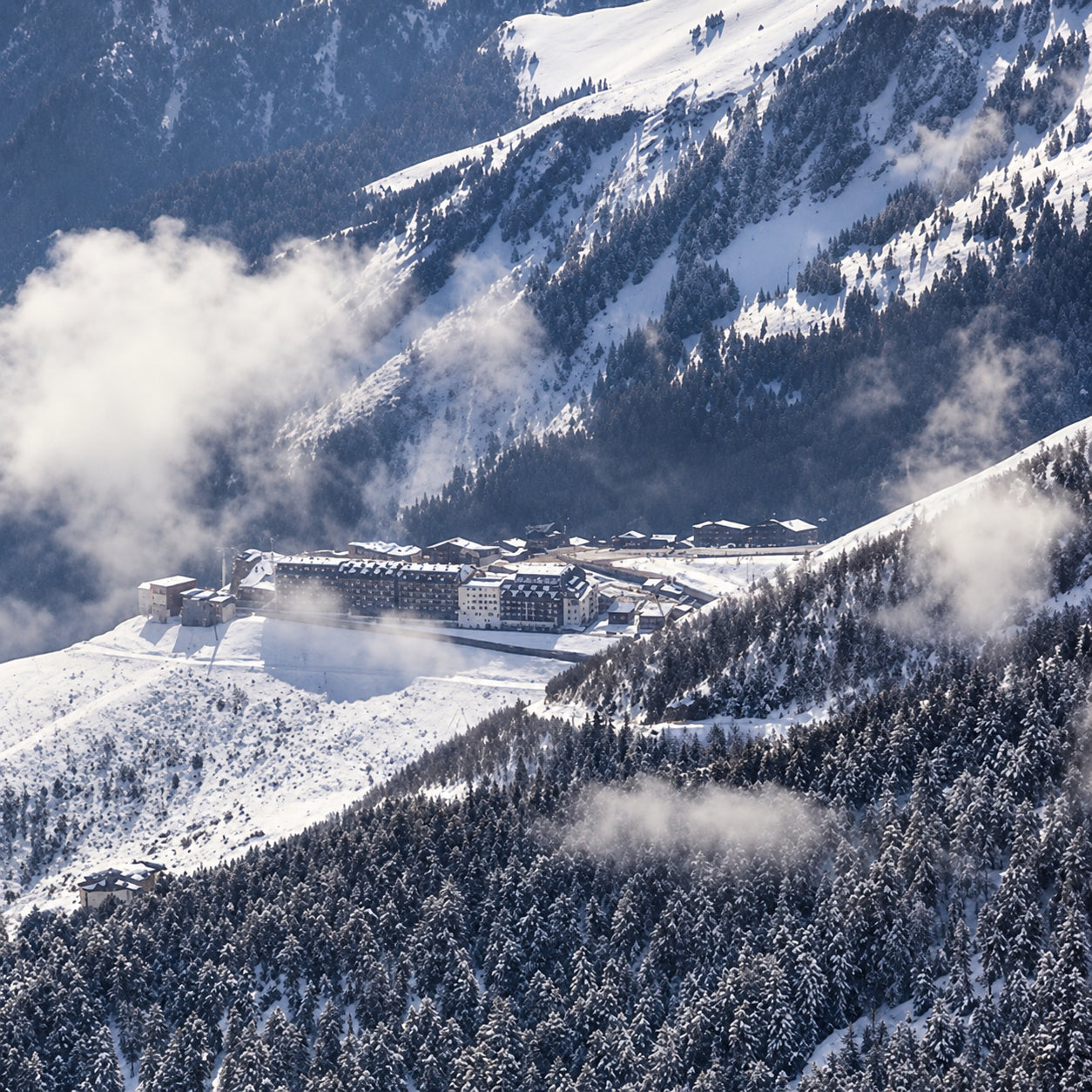 Panorama d’un domaine skiable entre neige, forêt et nuages